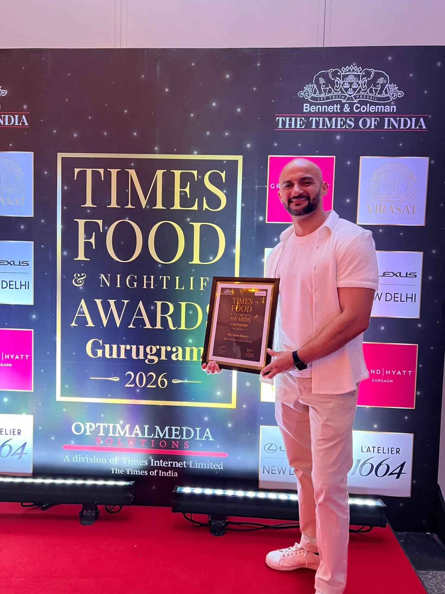 Rish Saini holding the Times Food & Nightlife Awards Gurugram 2026 certificate for Mrs Kaur's, Best Western Casual Dining