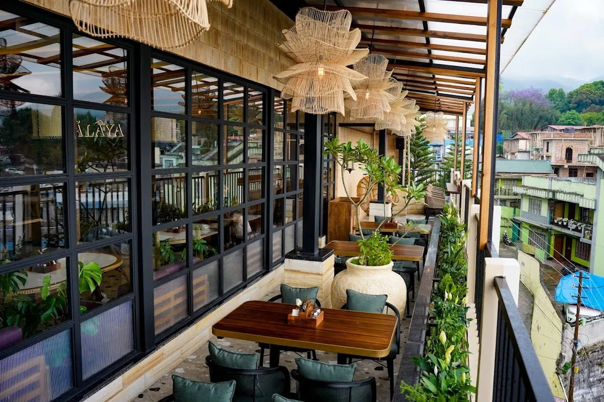 Ālaya's glazed balcony dining room with plants along the railing