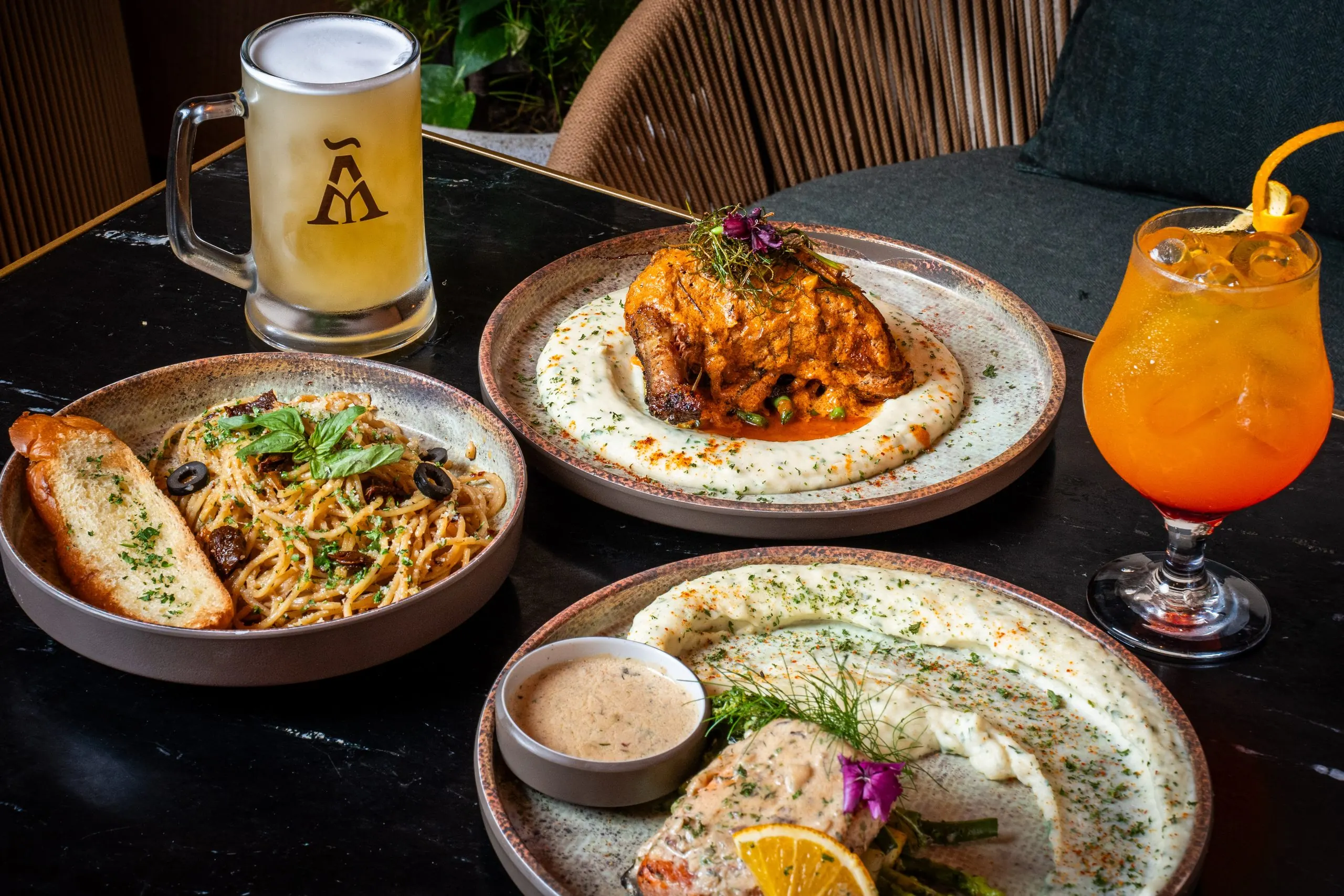 A table at Ālaya laid with plates, a beer and a cocktail