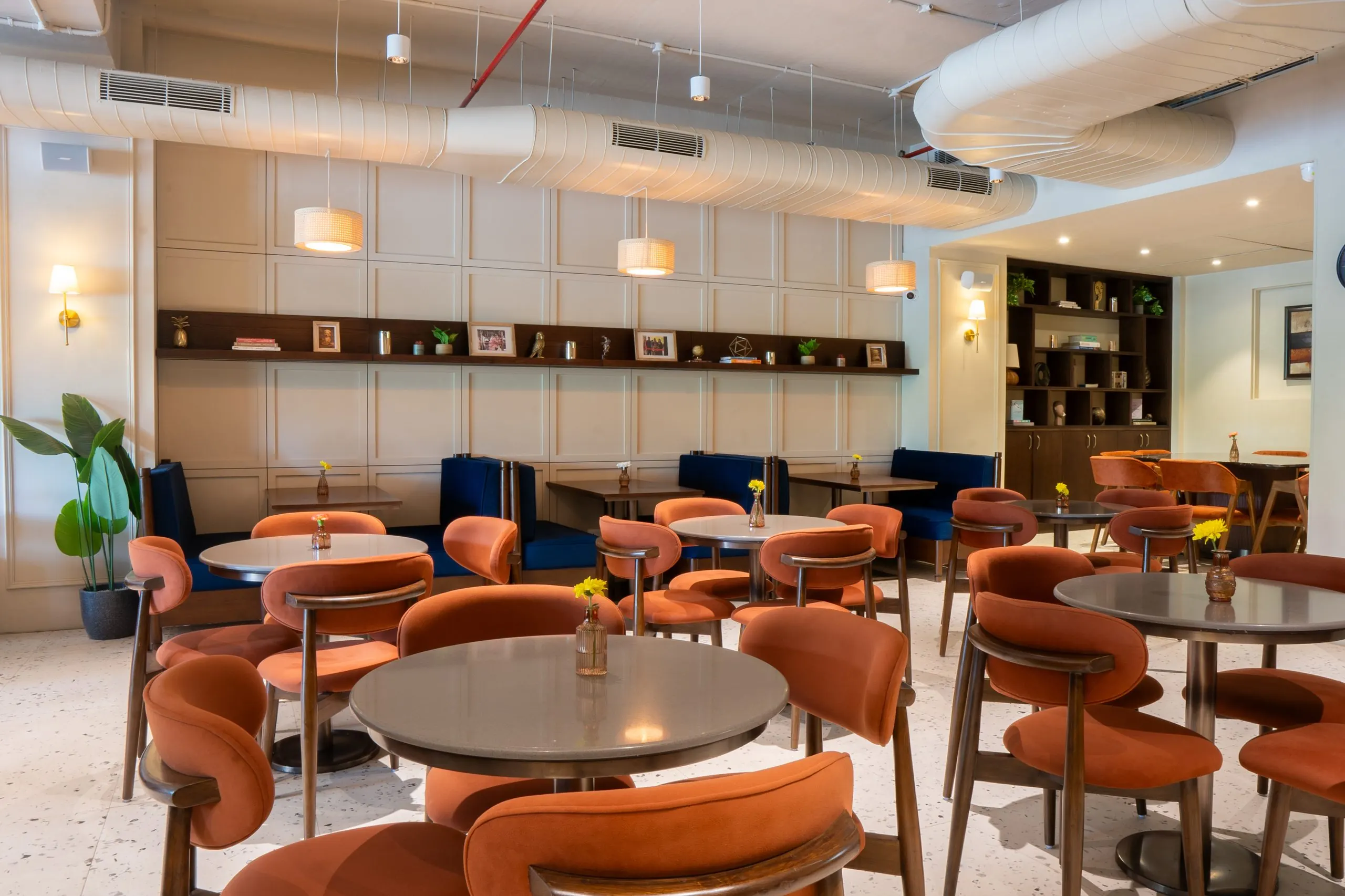 The café room at Mrs Kaur's, Golf Course Road, Gurugram, with round tables, banquettes and pendant lights