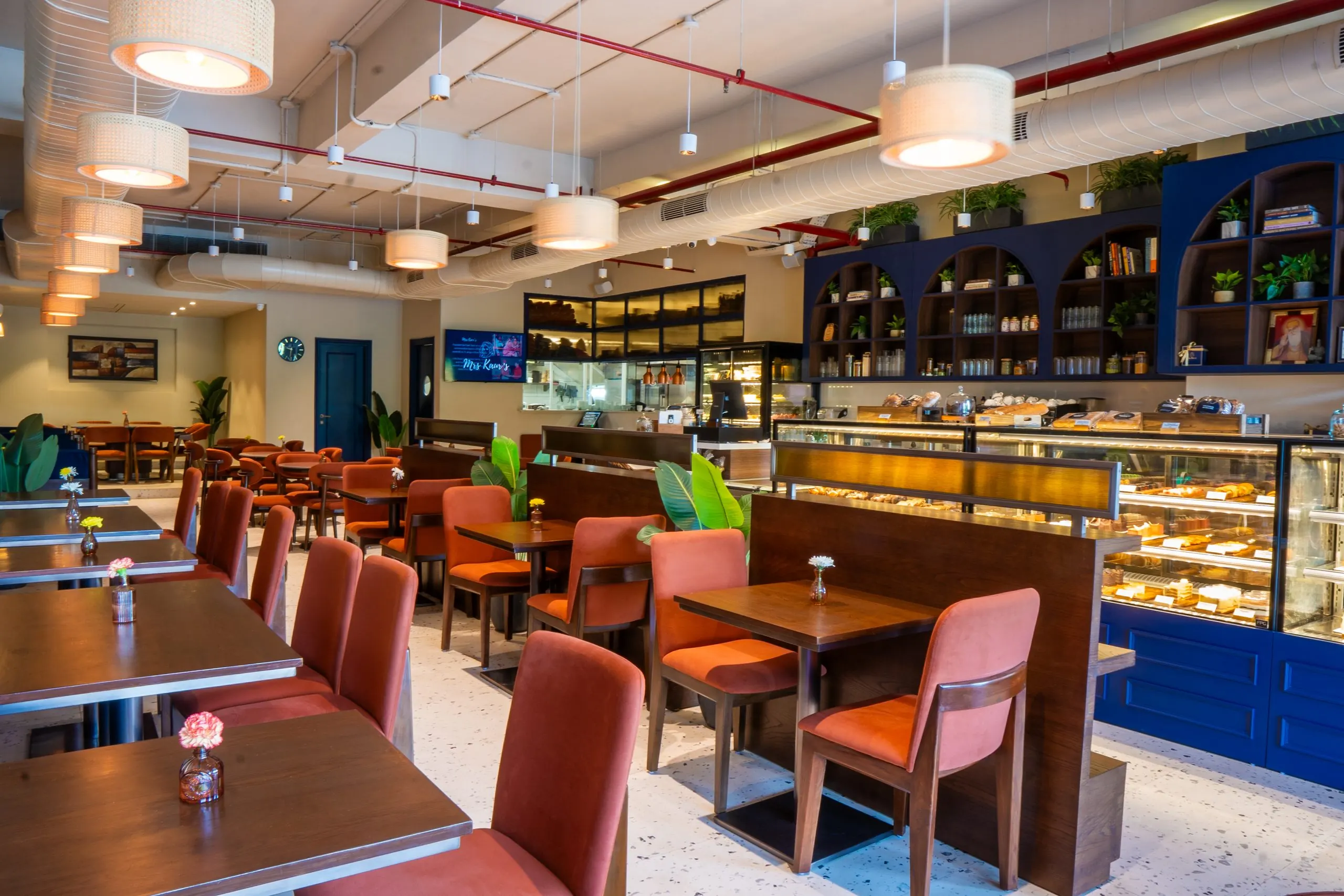 The dining room at Mrs Kaur's, Golf Course Road, with rust-coloured chairs, timber tables and a pastry counter