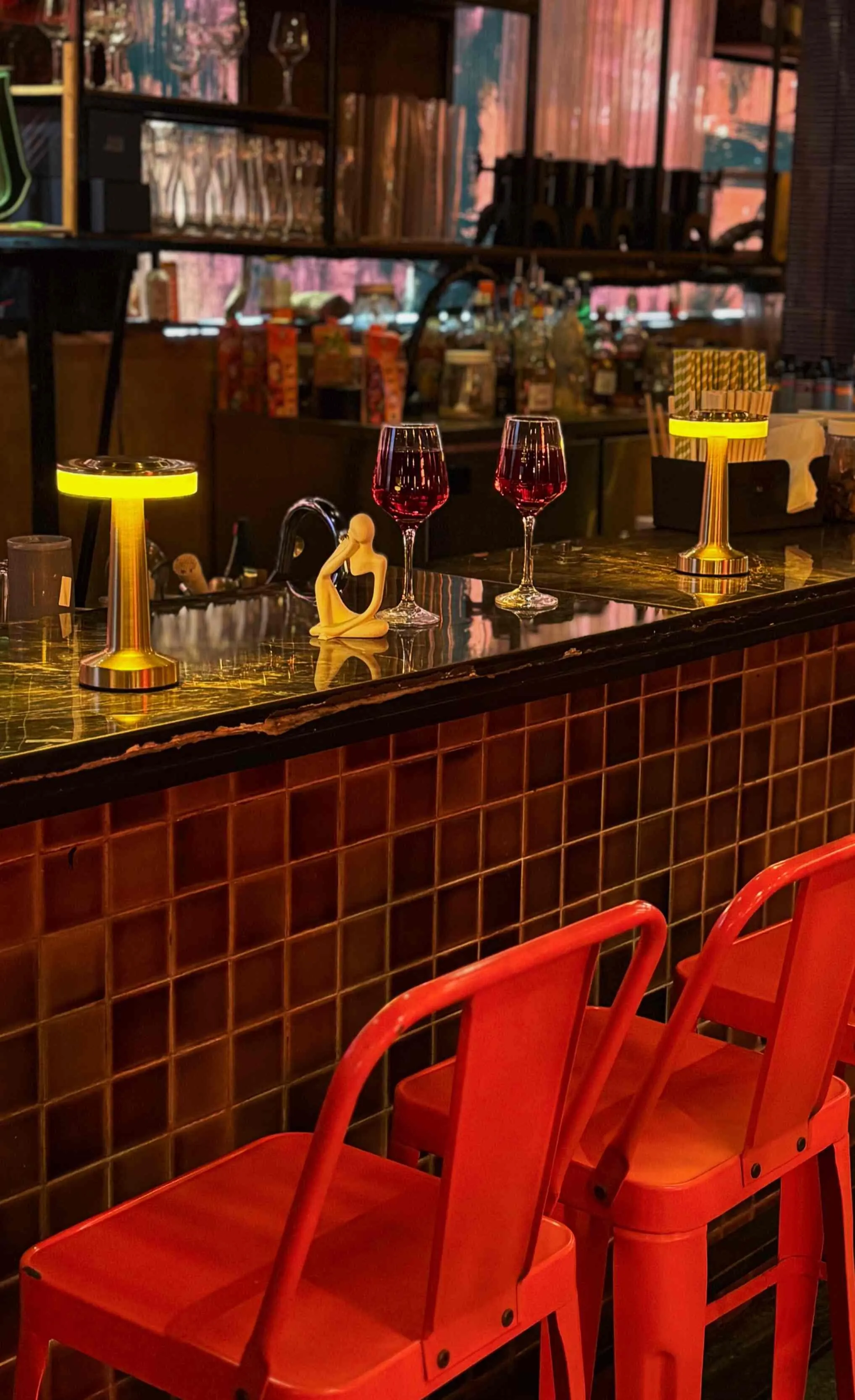 Detail of the Nuts & Brew bar: a mosaic-tiled front, red stools and brass table lamps