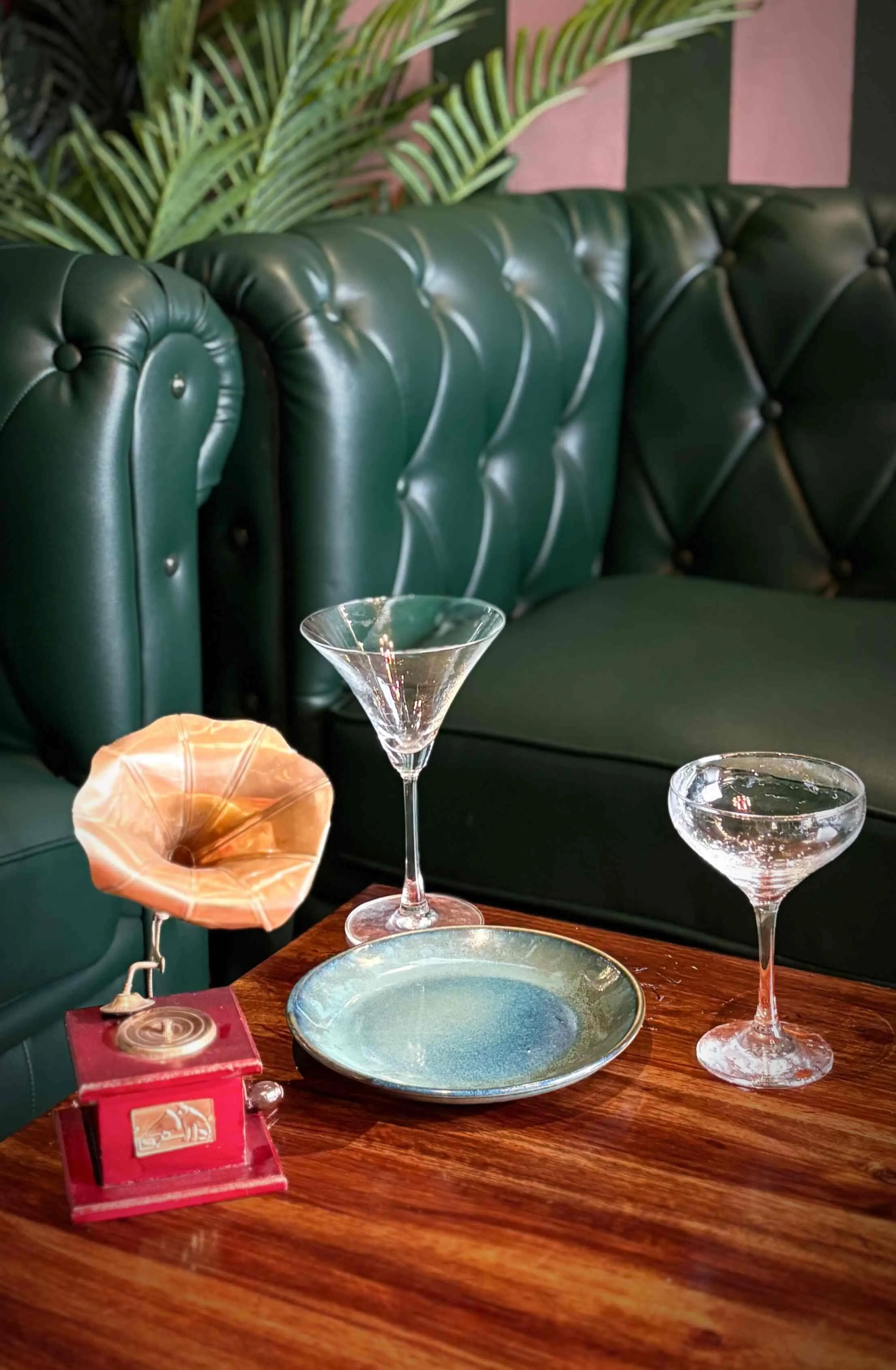 A green buttoned leather booth at Nuts & Brew with a timber table set with cocktail glasses