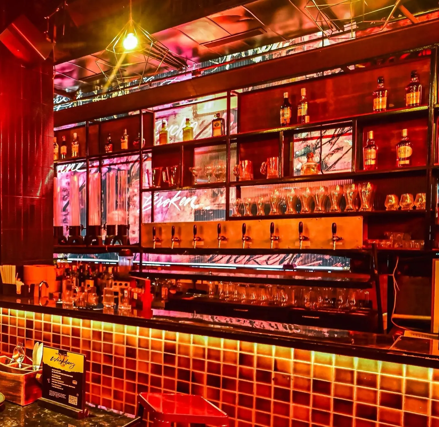 The back bar at Nuts & Brew with its row of beer taps above an amber mosaic-tiled counter