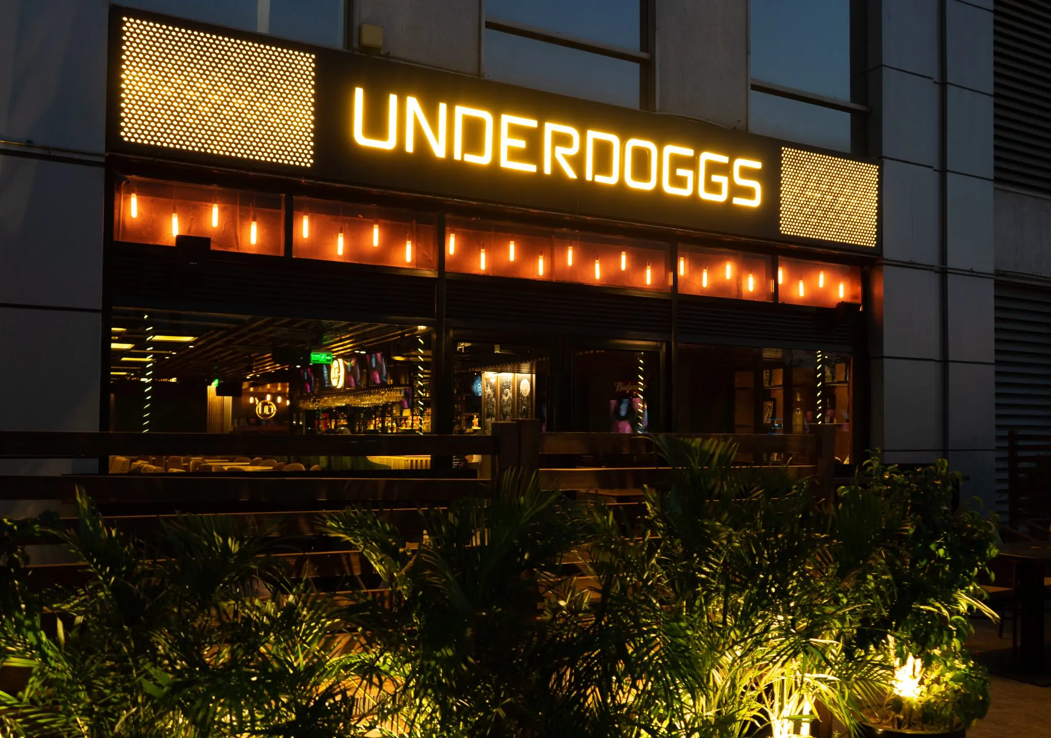 The illuminated Underdoggs fascia at Cyber Hub, Gurugram, at dusk