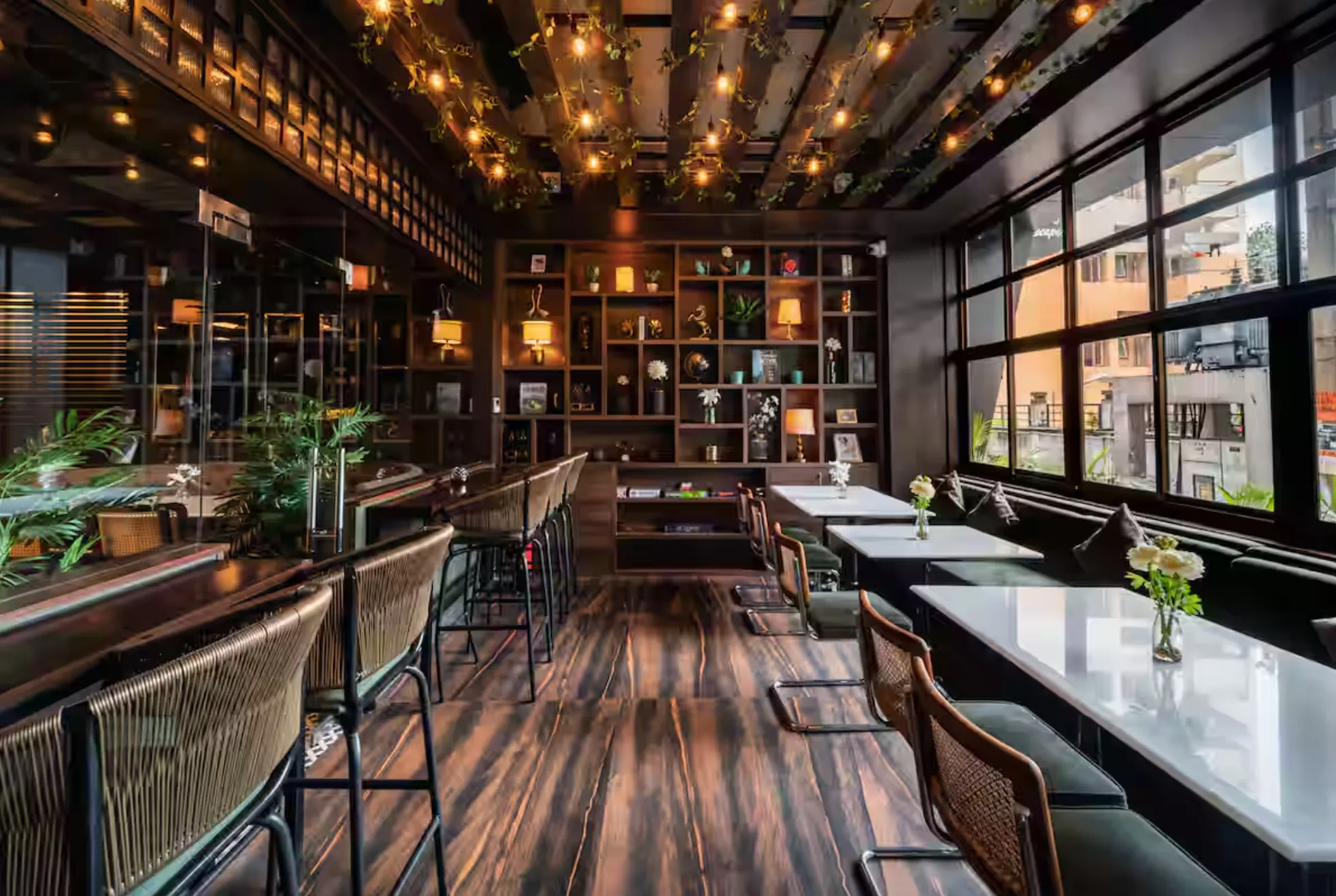 A window counter with high stools at Uptown Escape, under a ceiling of string lights and timber