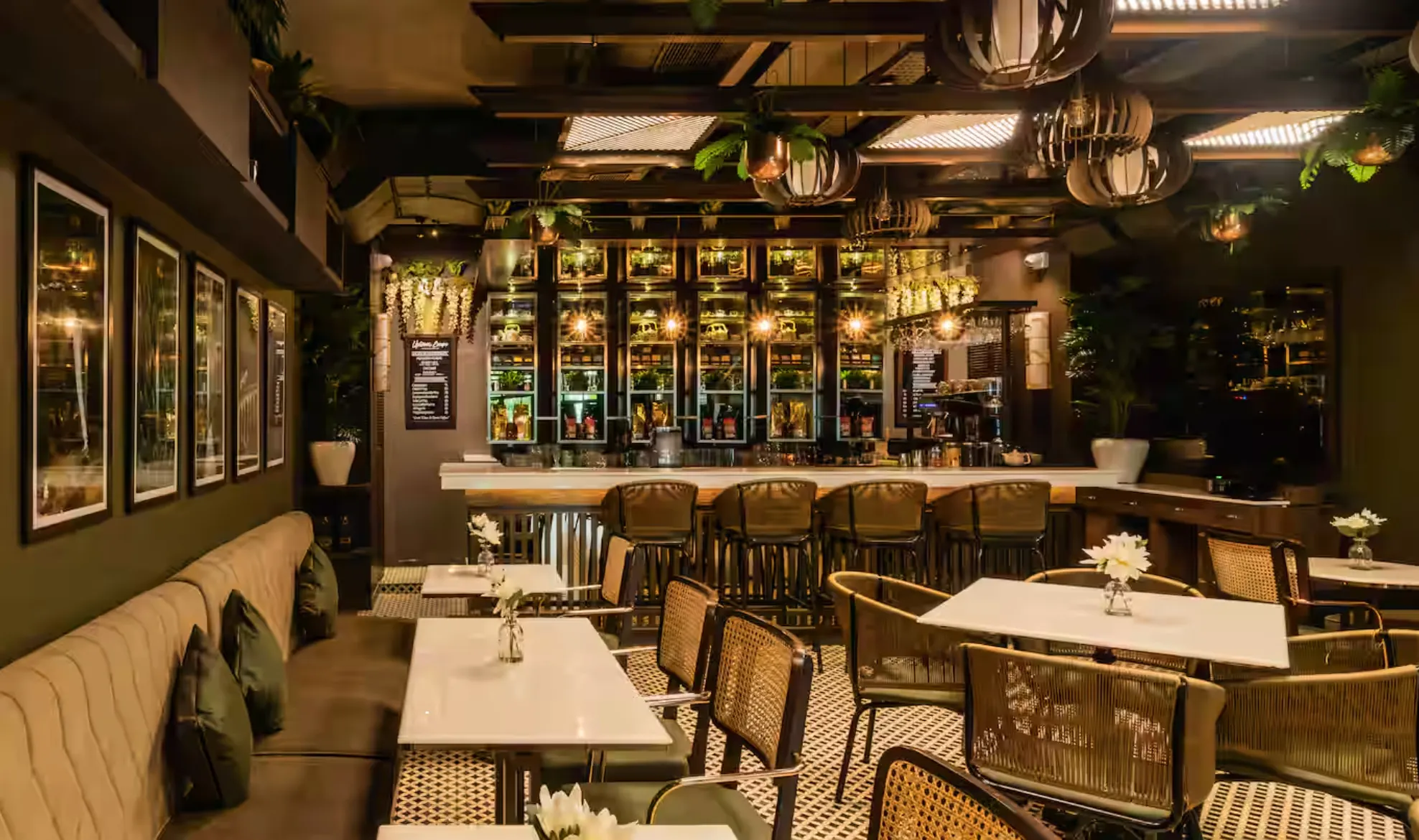 Uptown Escape's bar in its café set-up by day: the back bar holds teapots, tea and plants above banquettes and white-topped tables